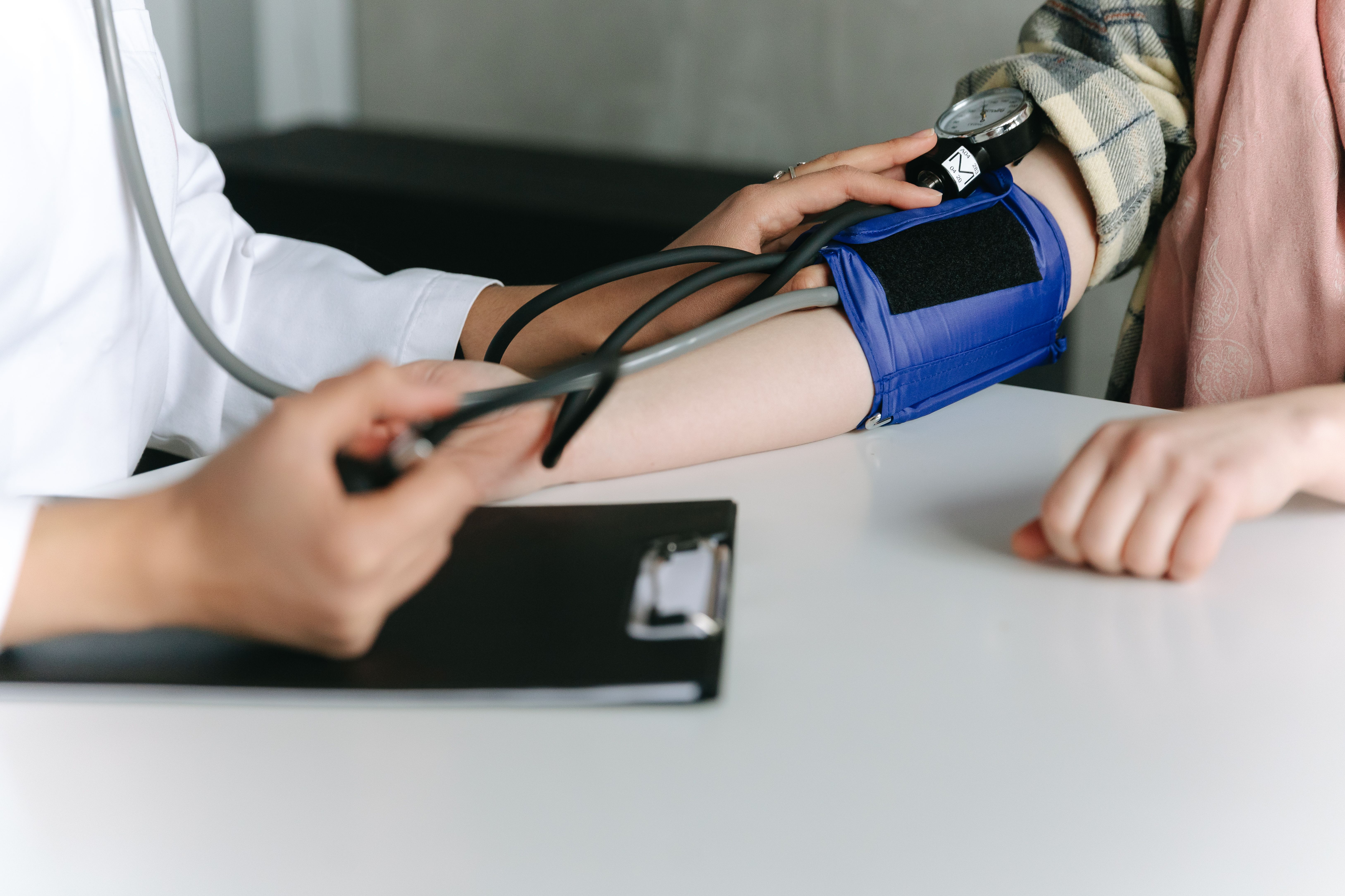 Healthcare worker checking a patient's blood pressure with a sphygmomanometer