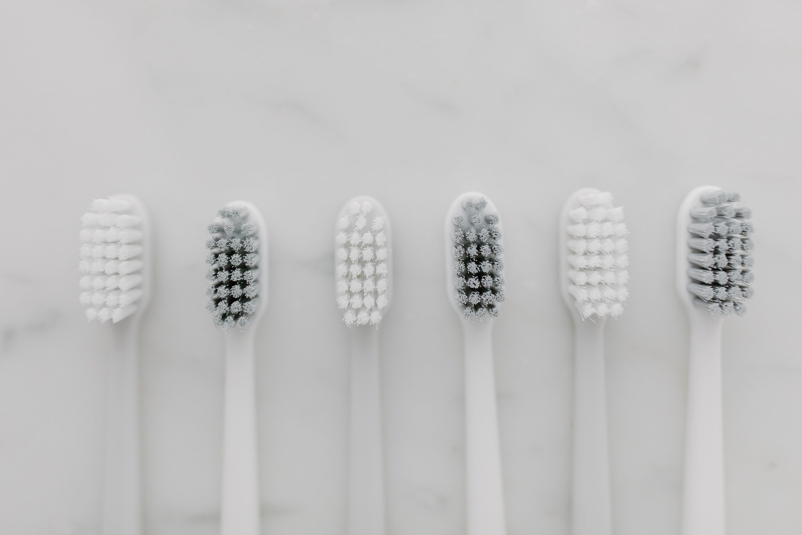 Clean white toothbrushes on a marble surface representing daily oral hygiene