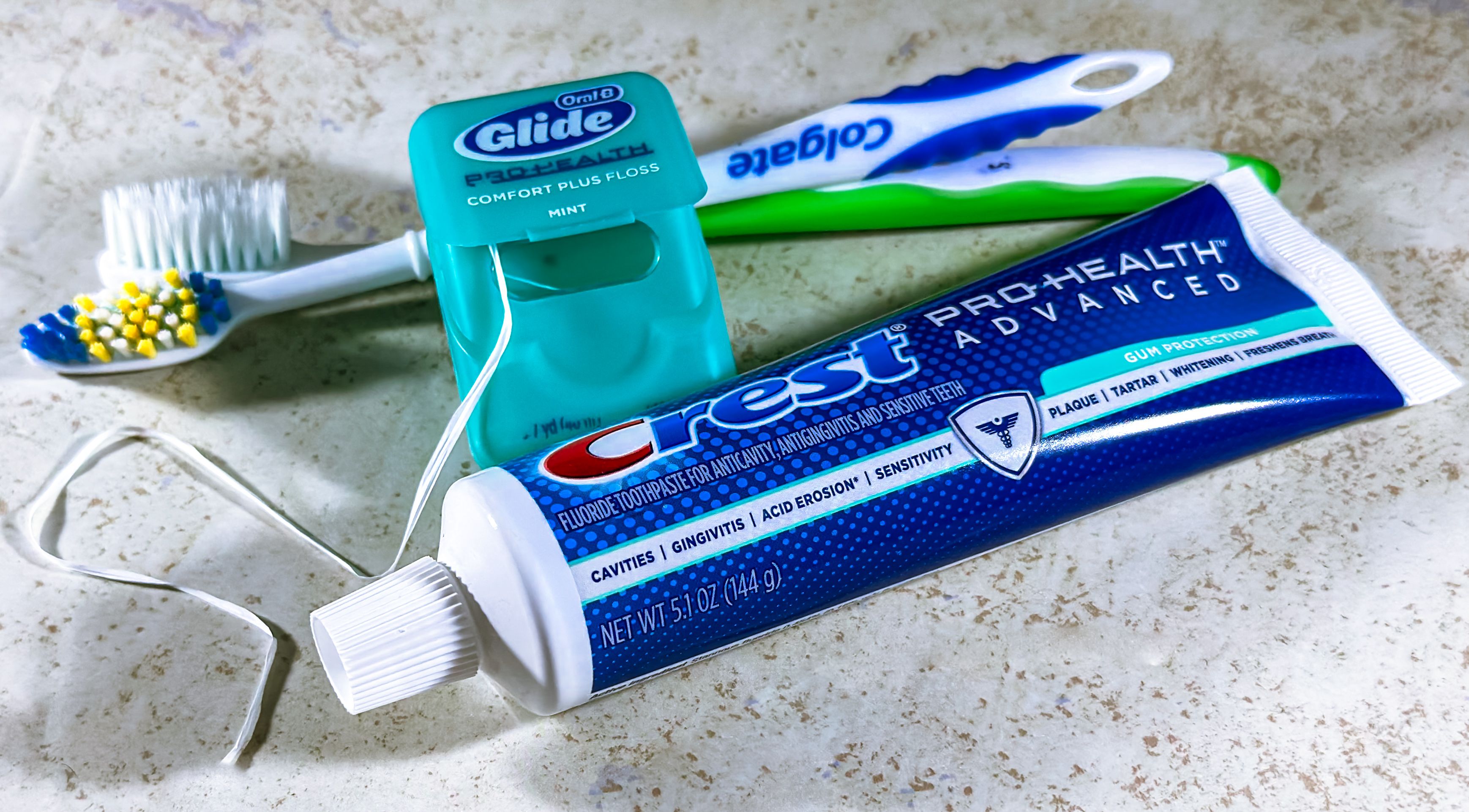Toothbrush, floss, and toothpaste arranged together for daily oral hygiene